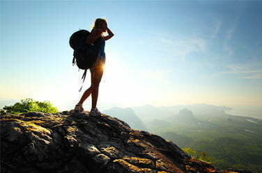 Partir « au vert » Randonneuse faisant une pause en haut d'un rocher
