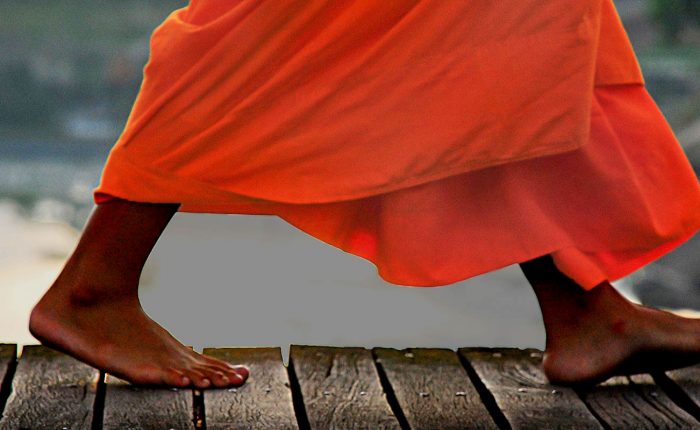 moine bouddhiste marchant sur un pont Laos