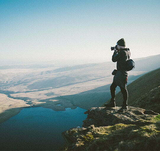 Photographe en haut d'une montagne prenant une photo de la vallée