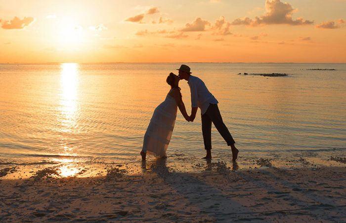 Couple s'embrassant sur la plage pendant le coucher de soleil